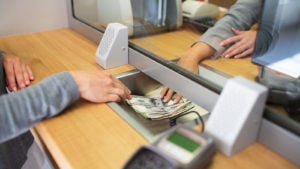 bank customer sliding money to teller at bank desk. promising bank stocks