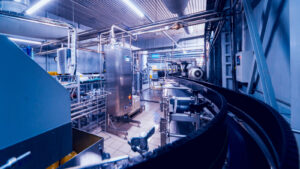 A photograph of the inside of a factory showing machinery and conveyer belts representing AIMC Stock.