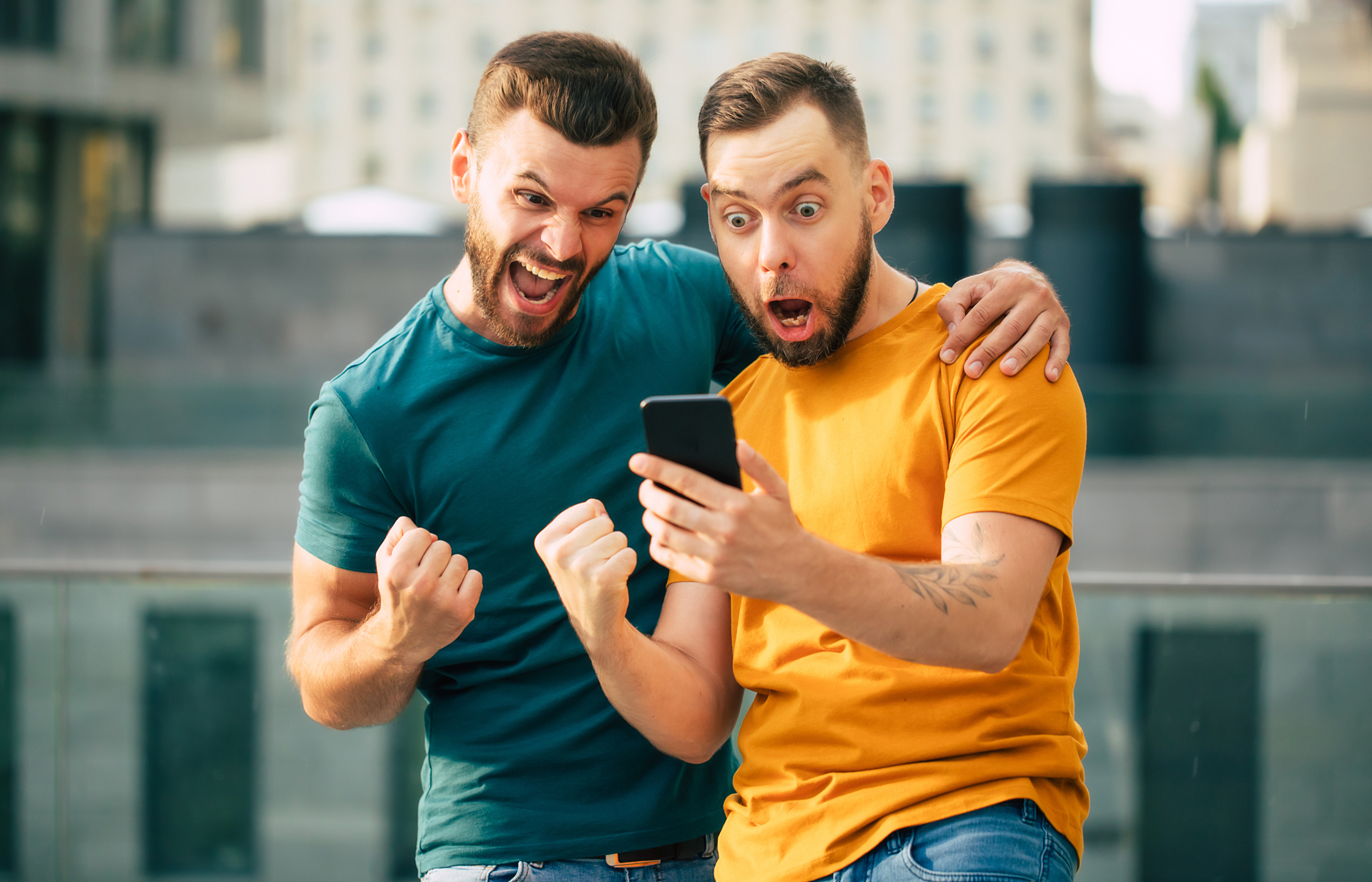 Two people looking at phone and cheering.