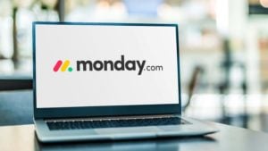 The Monday.com (MNDY) logo is displayed on a laptop screen.