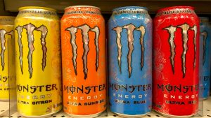 Grocery store shelf with 16 ounce cans of Monster brand energy drinks.