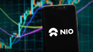 NIO logo on the smartphone screen and the chart of stock market at the blurred background.