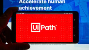 The UiPath logo on a smartphone in front of a computer screen.