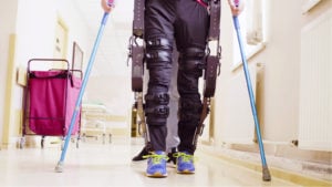 Image of a person using an exoskeleton and crutches to walk.