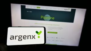 Person holding cellphone with logo of Dutch biotechnology company Argenx SE (ARGX) on screen in front of business webpage Focus on phone display