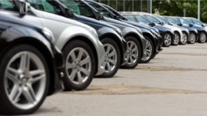 An angled side view of a row of parked cars. automotive stock picks