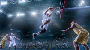 A basketball player makes a slam dunk in a crowded arena.