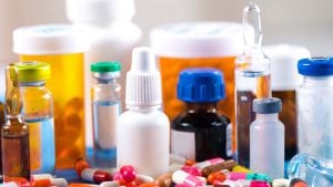 A variety of pills, pill bottles, and droppers arranged on a table in multiple bright colors.