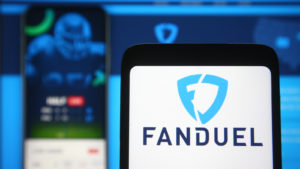 FanDuel logo of a sports betting company is seen on a mobile phone screen in front of FanDuel website on background.