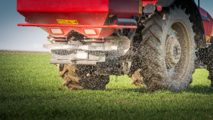 A tractor spreading fertilizer over a farm field.