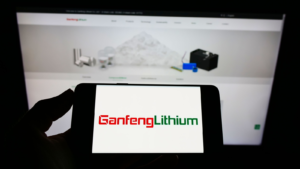 Person holding mobile phone with logo of Chinese company Jiangxi Ganfeng Lithium Co. Ltd. (GNENF) on screen in front of web page. Focus on phone display. Unmodified photo.