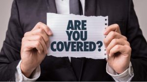 a person holds up a scrap of paper that asks "Are you covered?"