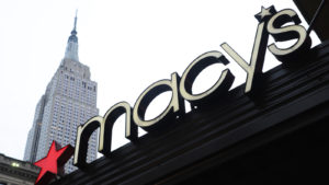 Macy's (M) logo on storefront in city with white sky behind