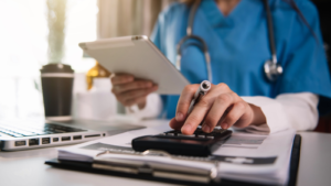 Doctor or physician calculating a patients medical bills at a desk. Medical bills, health costs, health expenses.