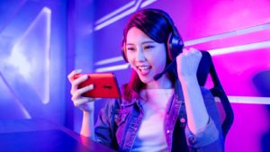 A mobile gamer cheering on her smartphone with neon background. MGAM stock