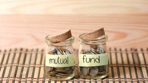 mutual funds to buy: Coins in jar. Writing Mutual Fund on two jar with wooden pallet background.