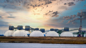 Several natural gas tanks with a sunrise in the background