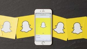 An apple iPhone showing the snapchat application alongside other snapchat logos. SNAP stock.