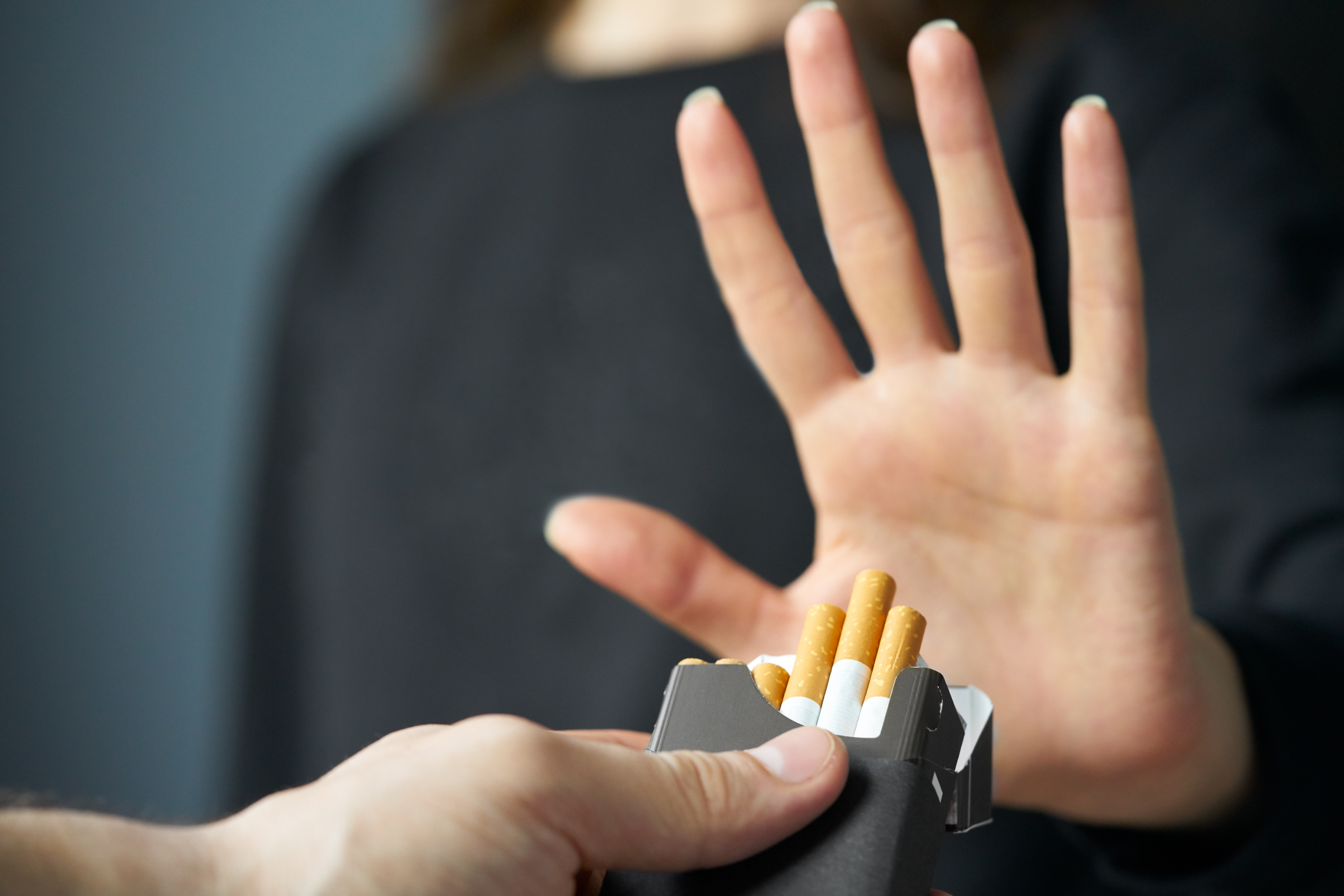 A person putting their hand up to reject an offer of tobacco cigarettes.