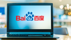 An image of a laptop on a table with the screen showing the red and blue logo for Chinese Internet company "Baidu", with the background being blurred.