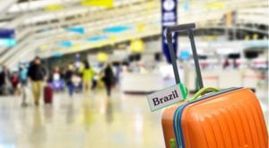 orange luggage in an airport with the word Brazil on it