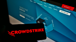 Person holding smartphone with logo of US software company CrowdStrike Holdings Inc. (CRWD) on screen in front of website. Focus on phone display. Unmodified photo.