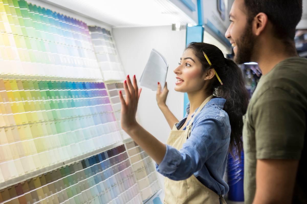 Two people looking at different paint color shades in a hardware store. 