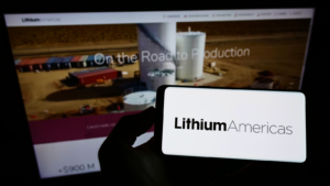 Person holding smartphone with logo of Canadian company Lithium Americas Corp (LAC) on screen in front of website Focus on phone display.
