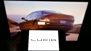 Someone is viewing a red Lucid (LCID) Air car on a computer screen while holding a phone that says Lucid