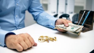 Man buying gold jewellry, pawn shop and us dollar banknotes