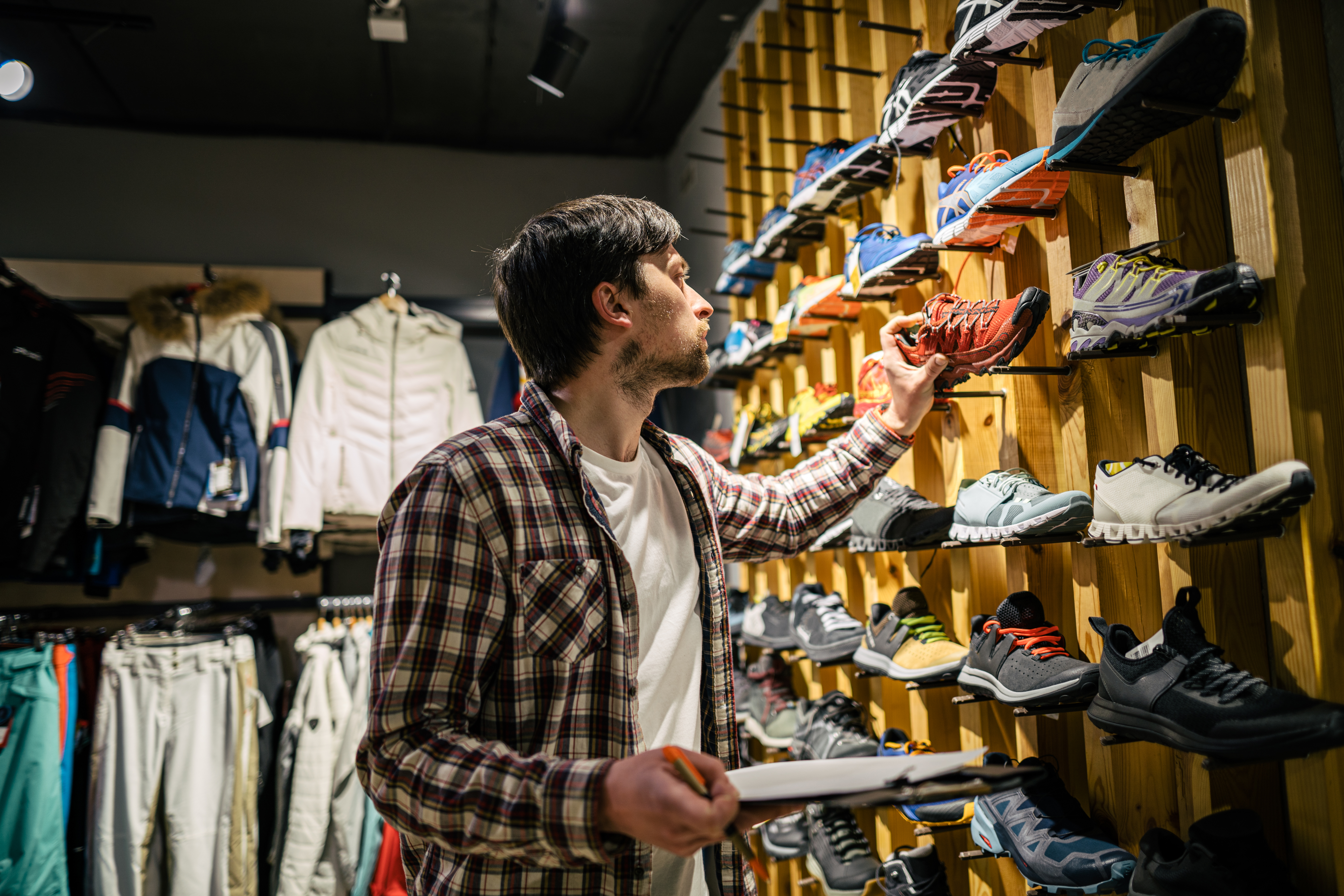 A person looks at sneakers on the wall at a store.