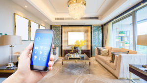 A hand holds a smart phone up with a fancy living room behind it.
