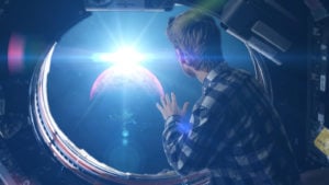 Person looking through space capsule's cabin window into space. best space stocks to buy