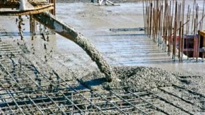 Image of wet concrete being poured onto a foundational structure