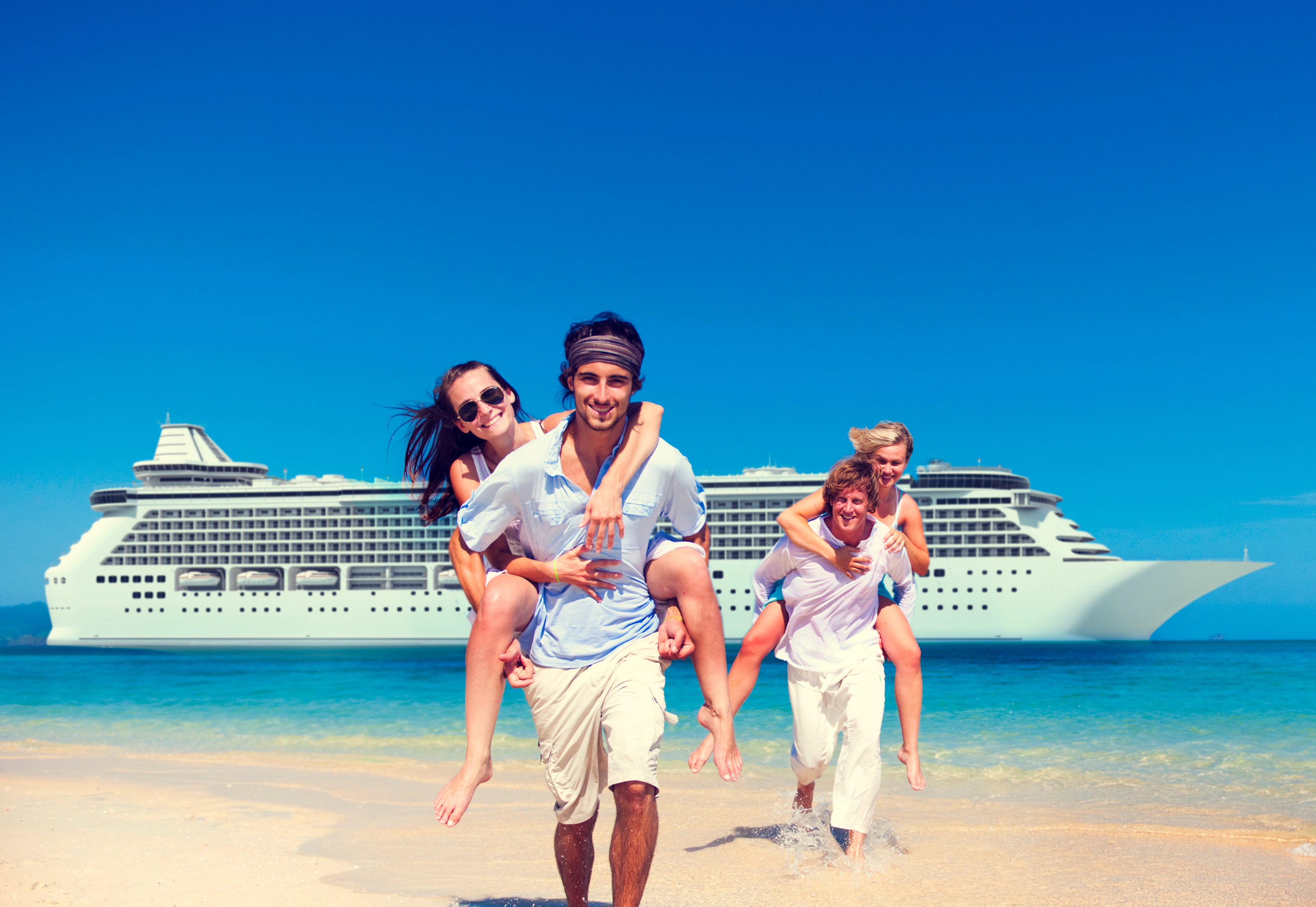 Two couples playing on the shoreline with a cruise ship behind them.