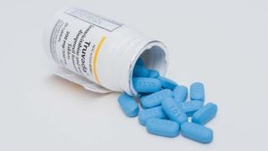 An image of a knocked over Truvada pill bottle will blue pills falling out.
