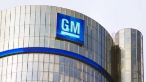 Image of General Motors (GM) logo on corporate building with clear sky in the background.