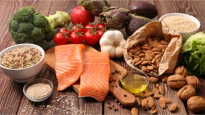 Healthy food including salmon, almonds, garlic, broccoli, avocado, and lettuce