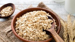 otly stock Rolled oats or oat flakes in bowl with wooden spoons