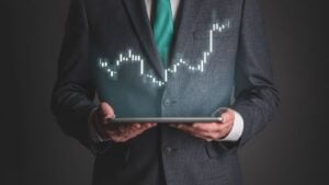 man in suit holding a tablet with graphic above showing oversold stocks to buy