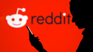 Silhouette man using smartphone with Reddit (RDDT) logo on blurred background is an American social news aggregation, content rating, and discussion website.
