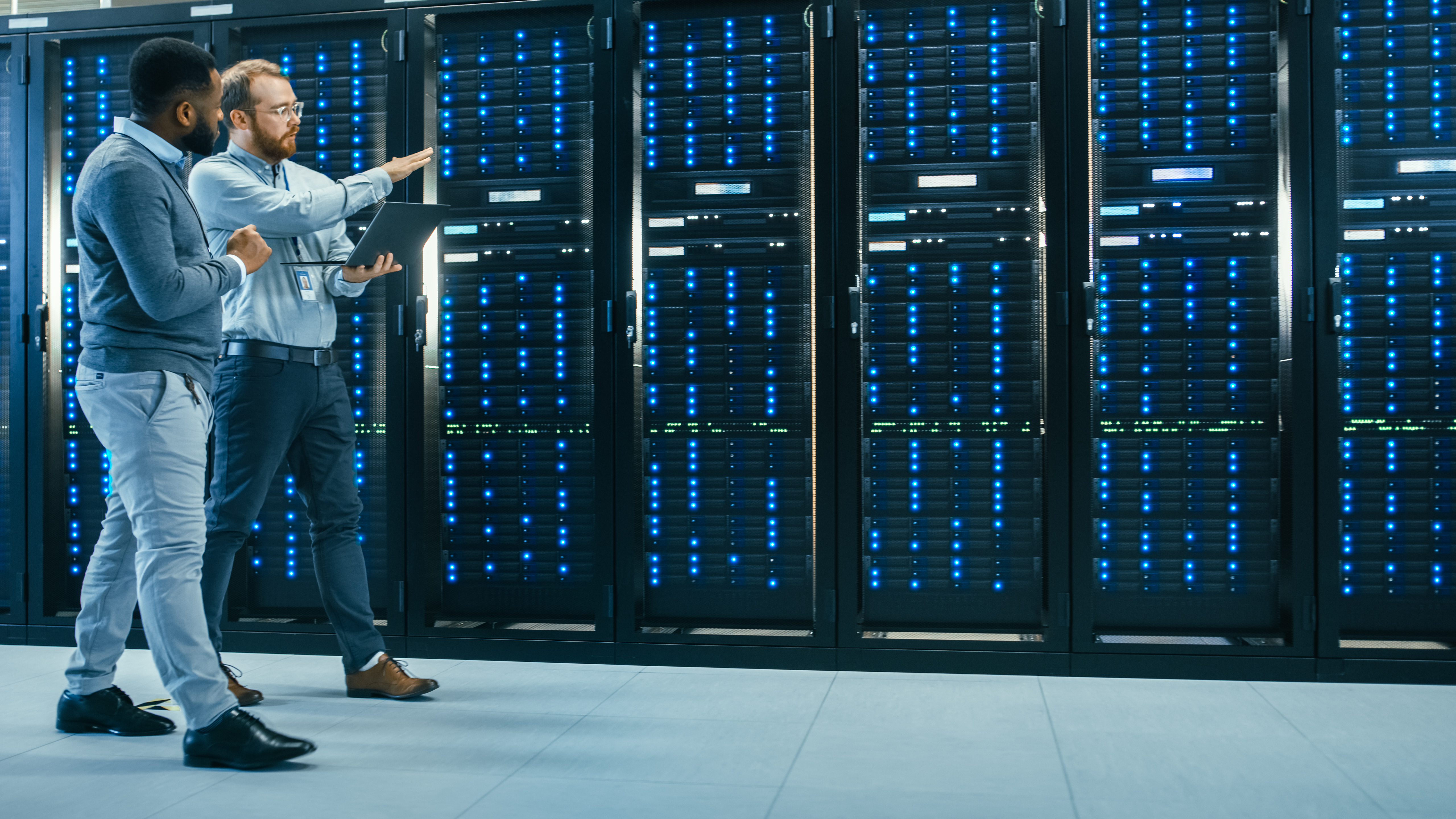 Two people working inside of a data center.