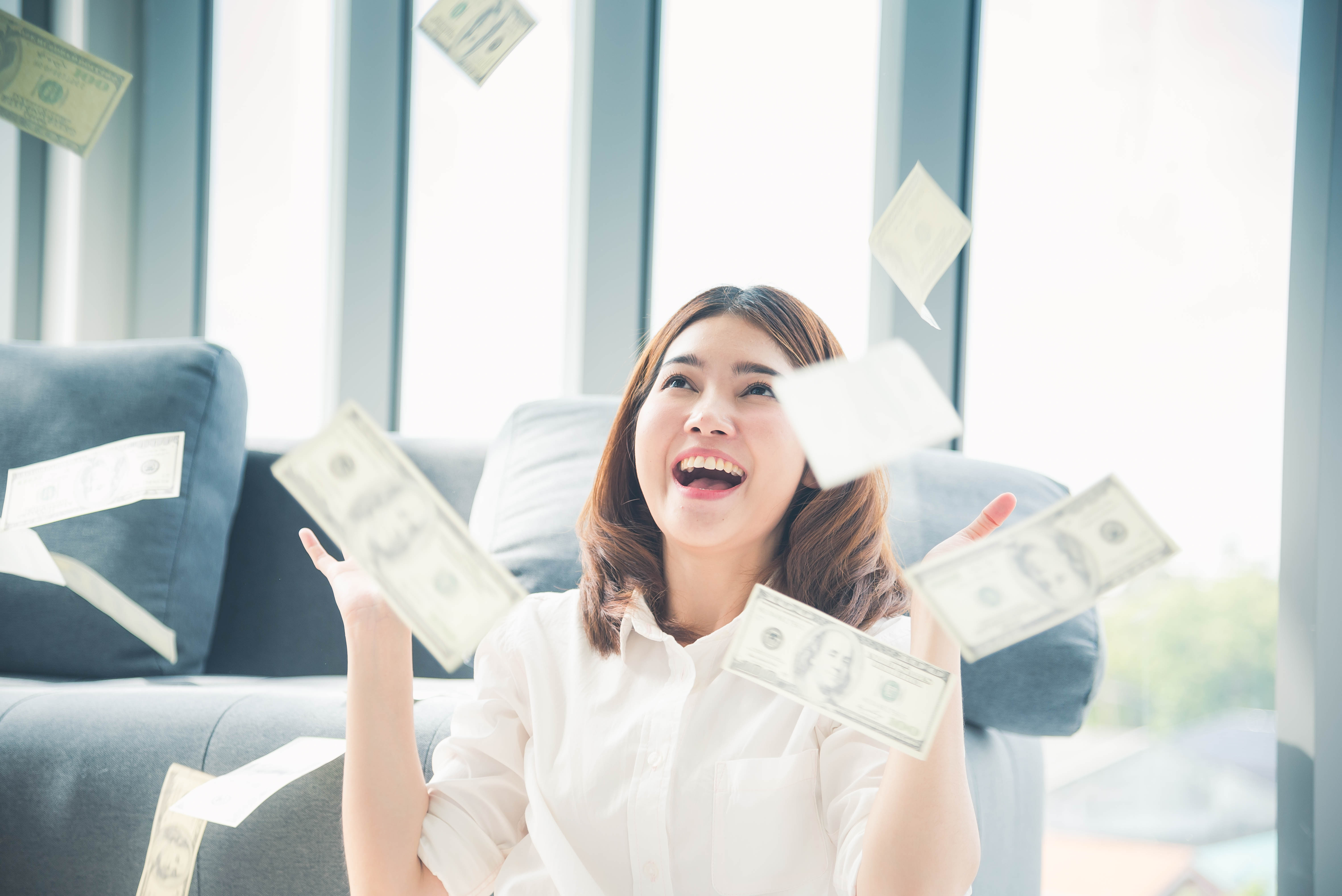 A person celebrating as money rains on them.