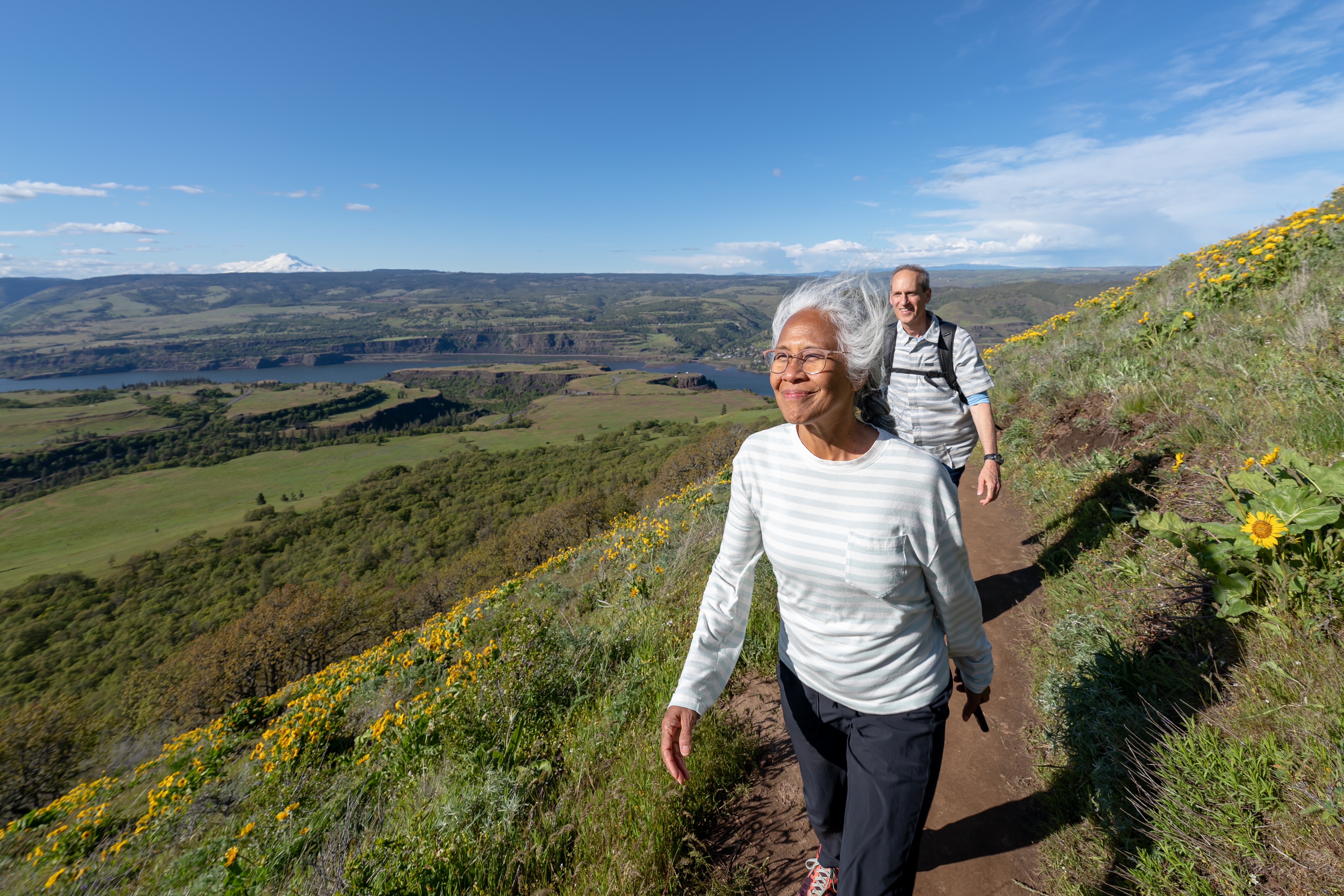 Two people walking outside on a dirt path.