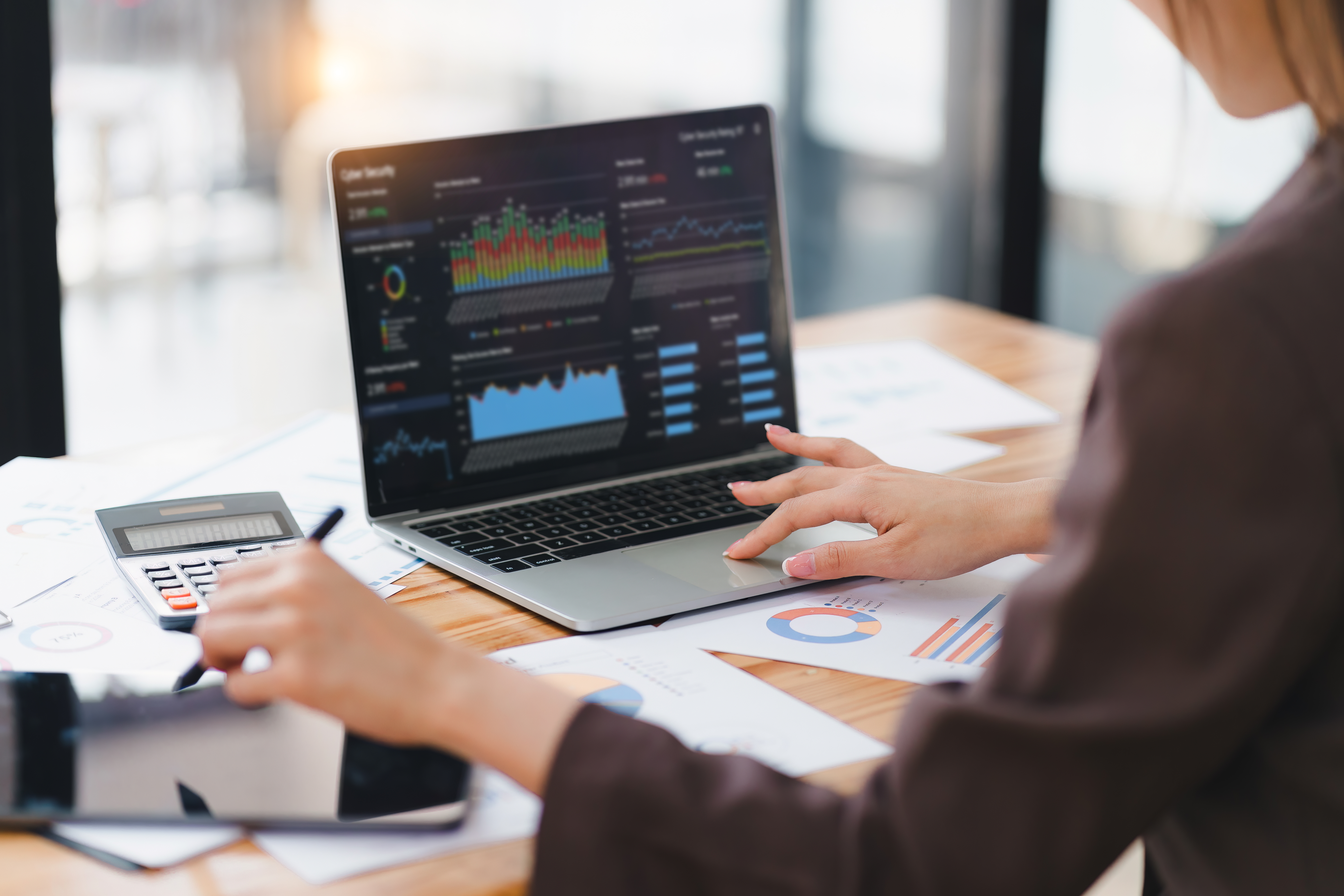 Someone sitting at a desk looking at charts and graphs on a laptop.