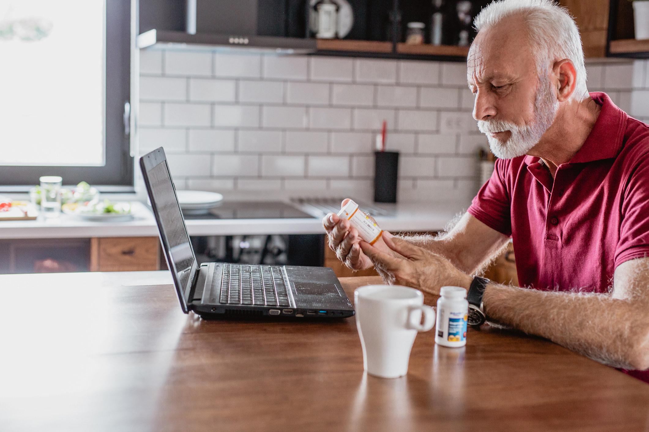 Person looking a prescription bottle at kitchen table.