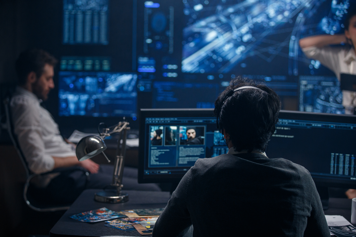 Two people in a room full of screens.